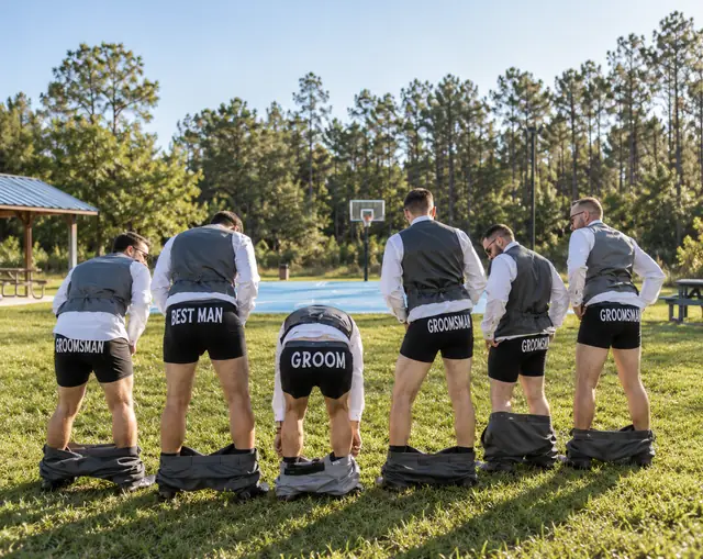 The groom and his groomsmen sharing a playful moment on the lawn
