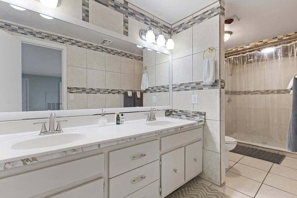 Bathroom with double-sink vanity, mirror and tiled walk-in shower