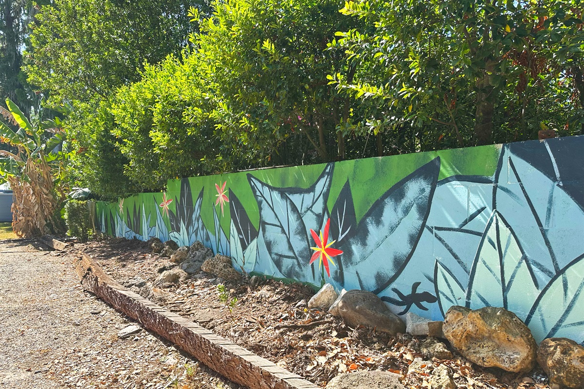 Tropical leaf mural painted along a garden wall