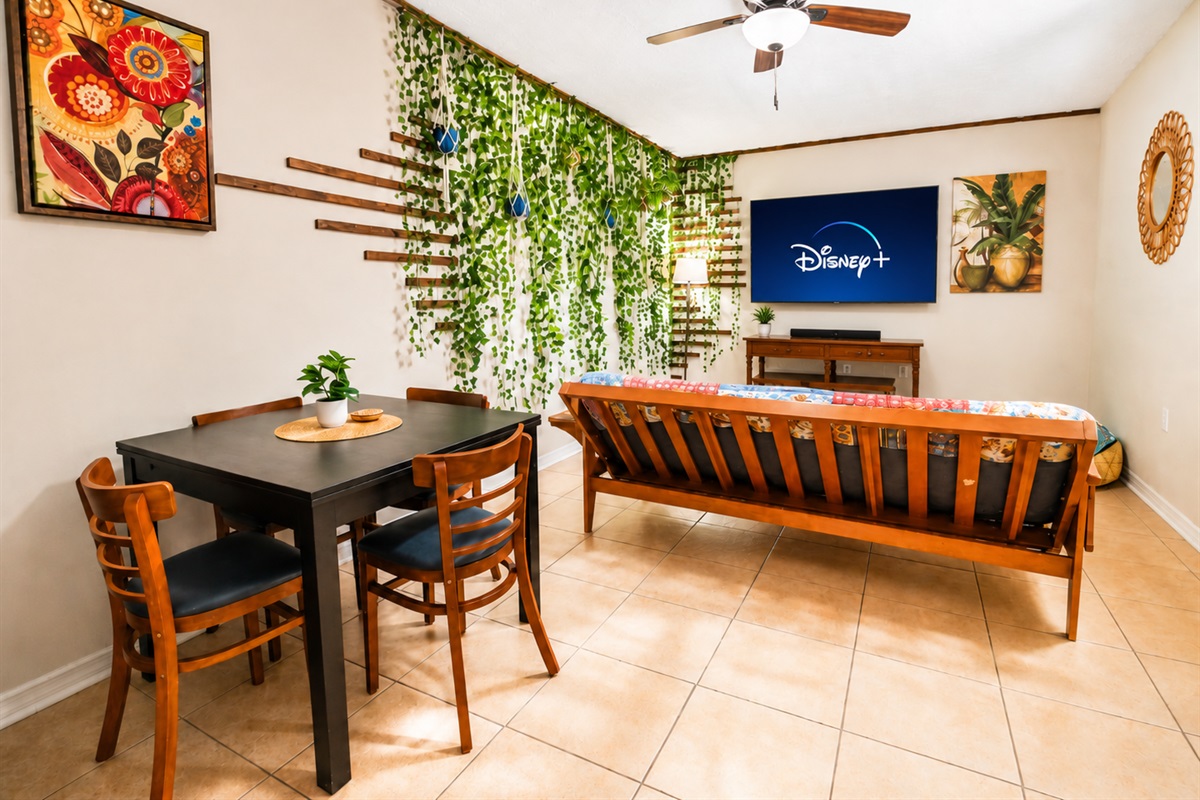 Casual living and dining space with futon, TV and greenery wall