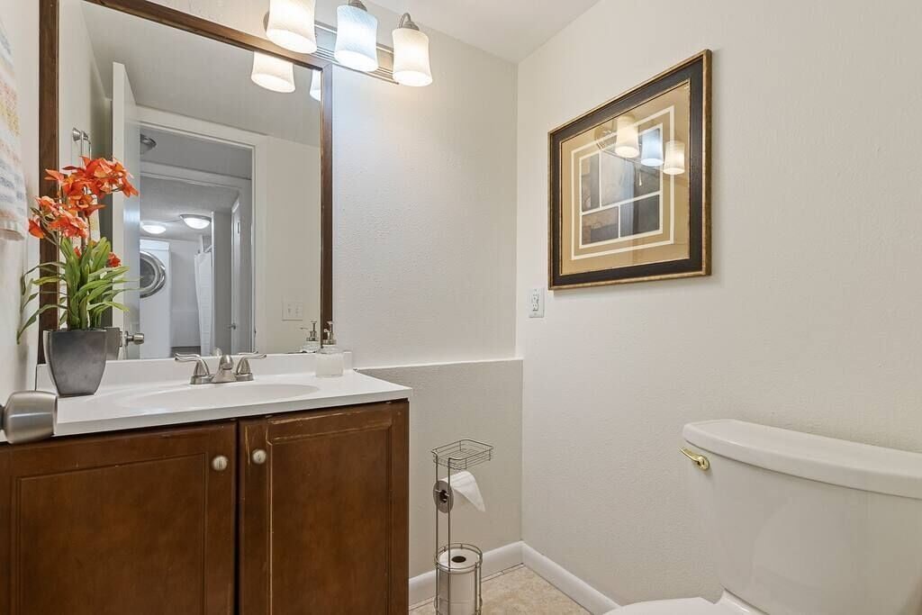 Bathroom with wood vanity, large mirror and toilet