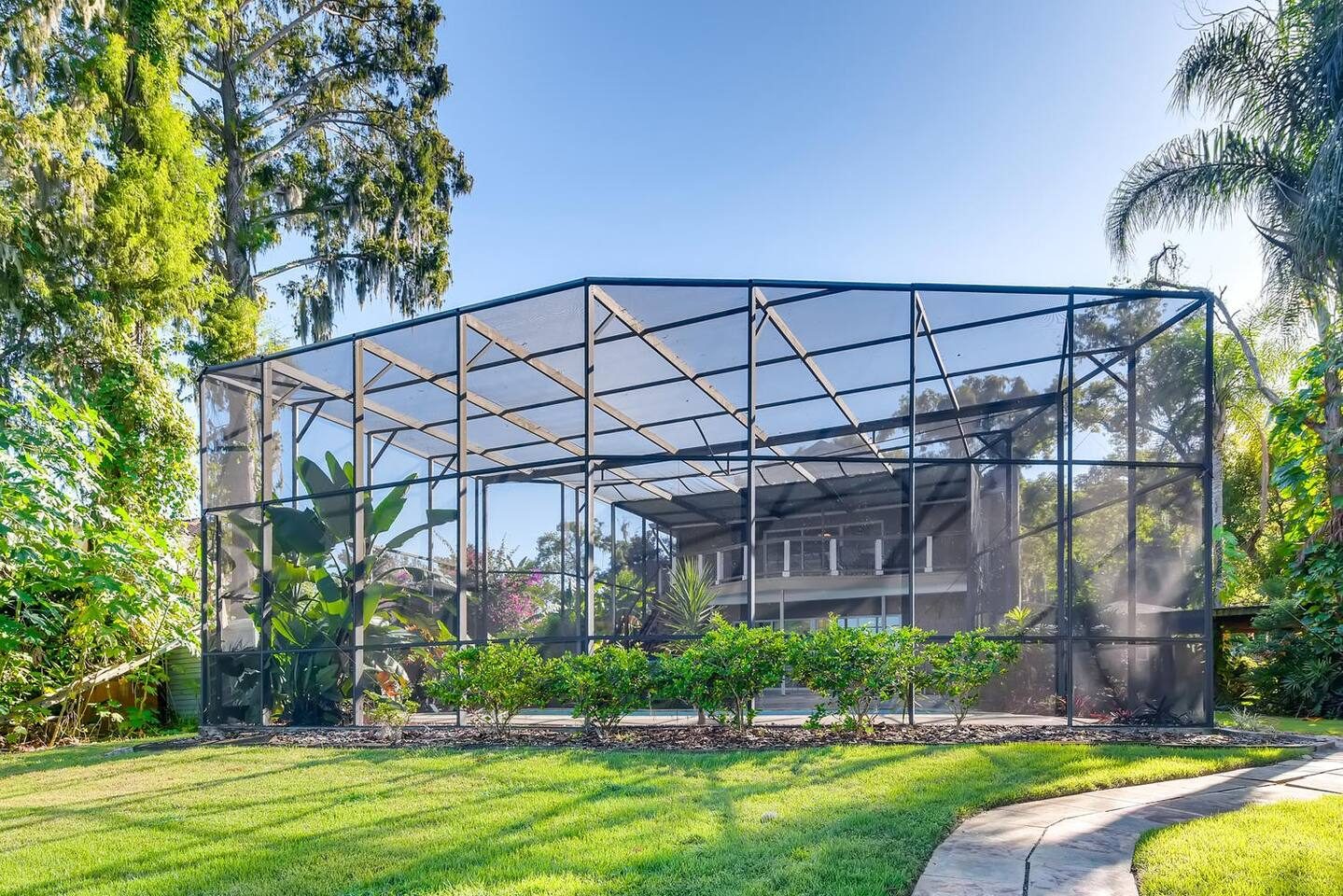 Lounge in the wide screened enclosure shaded by oaks.